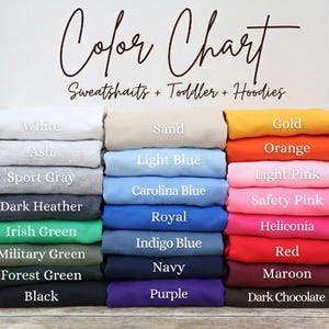 May include: Color chart for sweatshirts, toddler, and hoodies. The chart displays a variety of colors, including white, ash, sport gray, dark heather, Irish green, military green, forest green, and black. Other colors include sand, light blue, Carolina blue, royal, indigo blue, navy, and purple. Additional colors are gold, orange, light pink, safety pink, heliconia, red, maroon, and dark chocolate.