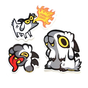 Puede incluir: Tres pegatinas de cabra de dibujos animados con diferentes expresiones. La primera pegatina muestra una cabra con un diseño en blanco y negro, respirando fuego con el texto "POOKA GOAT!" La segunda pegatina muestra una cabra con un diseño en gris y blanco, con la lengua roja fuera. La tercera pegatina muestra una cabra con un diseño en gris y blanco, con un ojo amarillo y la boca cerrada.