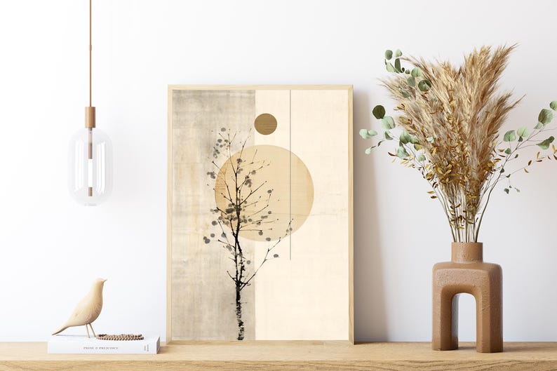 May include: A framed abstract art print featuring a beige and tan color palette with a stylized tree branch and a large circle. A decorative vase with dried plants and a wooden bird figurine are also visible.