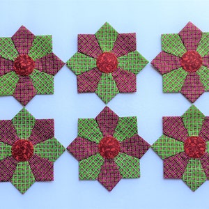 May include: Six handmade fabric flower blocks in shades of green and red. Each block is a star shape with a smaller red circle in the center.