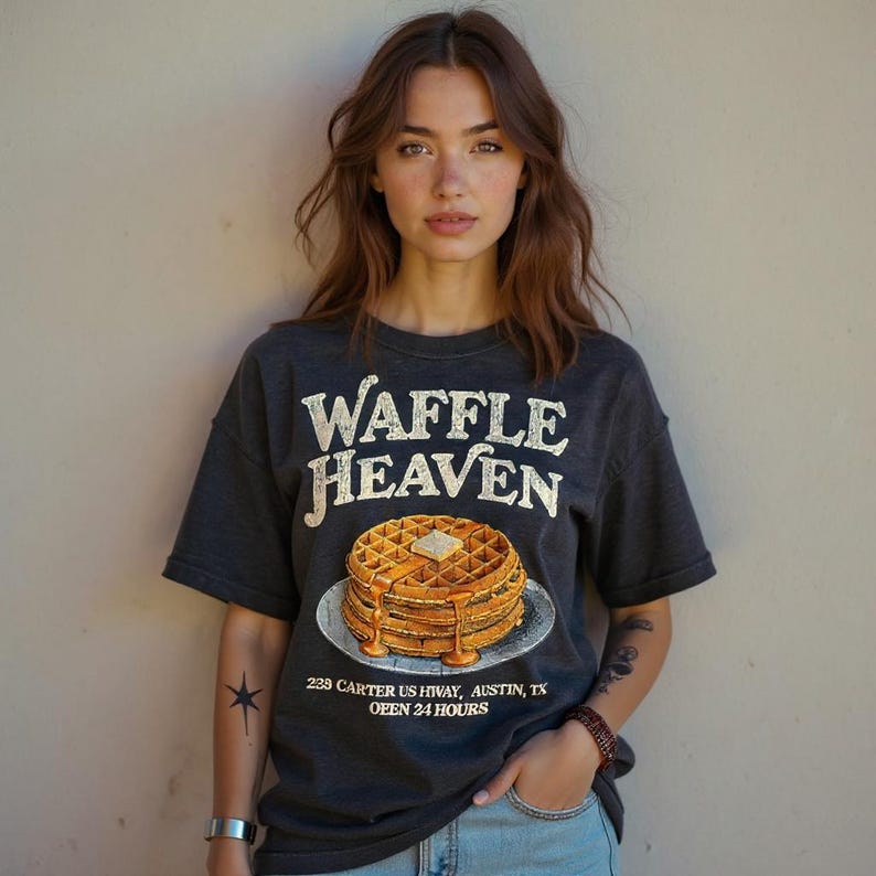 May include: Dark gray t-shirt with the text "Waffle Heaven" above a graphic of waffles with syrup. The shirt also includes the address "238 Carter US Hwy, Austin, TX" and "OPEN 24 HOURS".