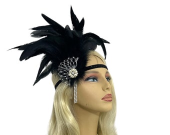 May include: A black feather headband with a sparkly rhinestone embellishment. The headband is worn on a mannequin with blonde hair.