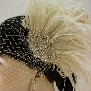 May include: A bridal hairpiece with a large, sparkly rhinestone cluster and a plume of ivory feathers.