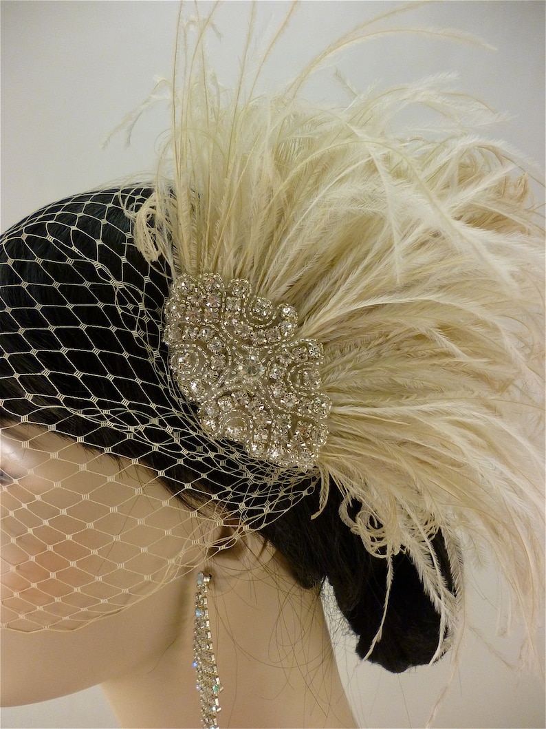 May include: A bridal hairpiece with a large, sparkly rhinestone cluster and a plume of ivory feathers.