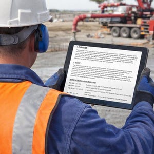 May include: A construction worker wearing a white hard hat, blue ear protection, and an orange safety vest, holding a tablet displaying text. A red concrete pump truck is visible in the background, suggesting a construction site.