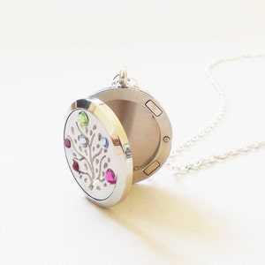 May include: Silver pendant necklace with a tree of life design and colorful gemstones. The pendant is open to reveal a small compartment inside.