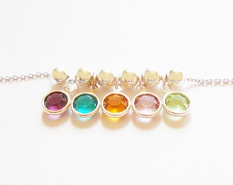 May include: A silver chain necklace with five round, colorful gemstones hanging from it. The gemstones are purple, teal, orange, pink, and green.