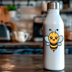 May include: A white insulated water bottle with a silver lid, featuring a cartoon bee design. The bee is yellow and black with blue wings. The bottle is on a wooden surface.