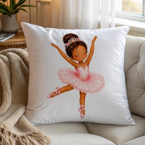 May include: A square white throw pillow featuring a centered illustration of a young ballerina with dark curly hair in a bun, wearing a pink tiara and a layered pink tutu with matching ballet slippers, posed with arms raised in a graceful dance.