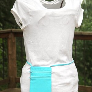 May include: A white t-shirt with a turquoise fabric pouch attached to a belt around the waist.