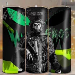 Puede incluir: Un vaso negro y verde con un soldado con una máscara de calavera, la palabra "GHOST" en verde y un diseño verde neón y negro. El vaso tiene una pajita plateada.
