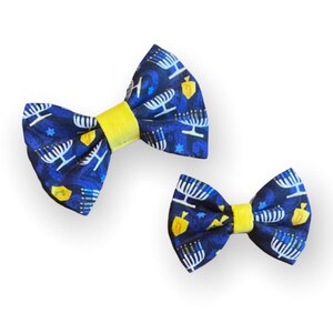 May include: Two blue and yellow bow ties with a menorah and dreidel pattern.