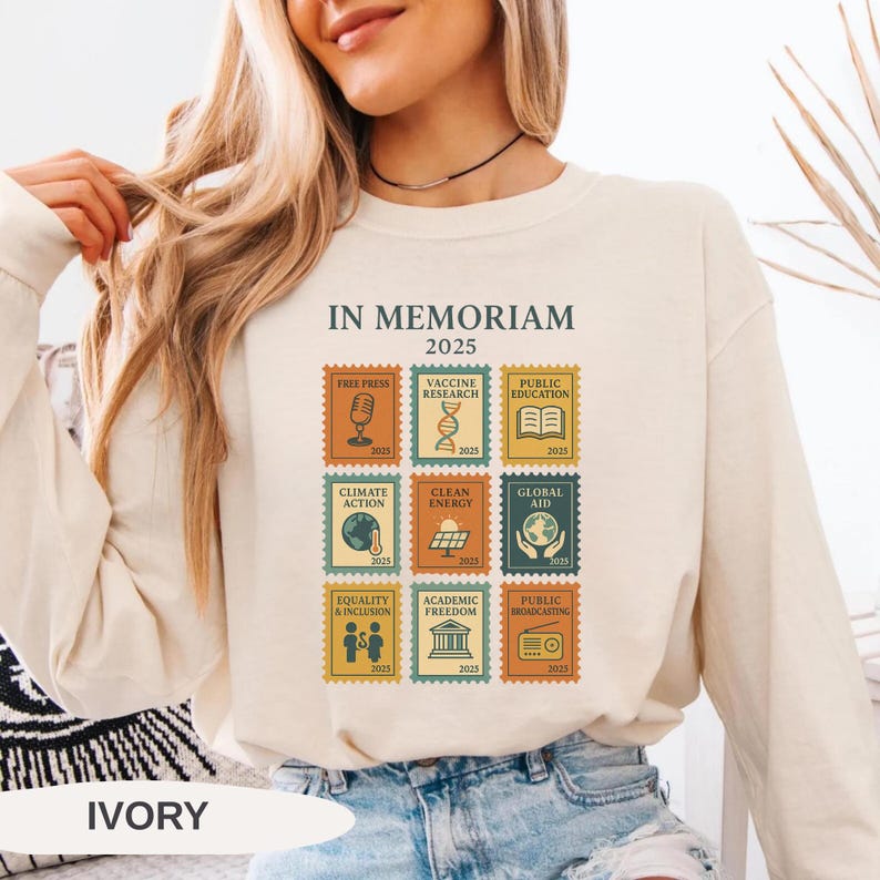 May include: Ivory-colored sweatshirt with a graphic of postage stamps featuring icons and text including "IN MEMORIAM 2025", "Free Press", "Vaccine Research", and "Public Education". The word "IVORY" is printed at the bottom.