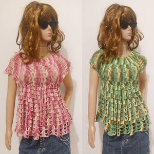 May include: Two handmade crochet tops. One is pink and cream, the other is green, yellow, and brown. Both have short sleeves and a cinched waist. The tops are displayed on mannequins wearing denim jeans.