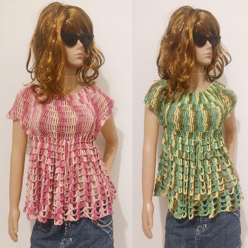 May include: Two handmade crochet tops. One is pink and cream, the other is green, yellow, and brown. Both have short sleeves and a cinched waist. The tops are displayed on mannequins wearing denim jeans.