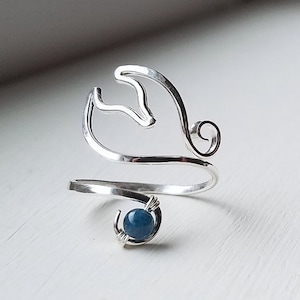 May include: A silver ring with a blue gemstone and a wave-like design.