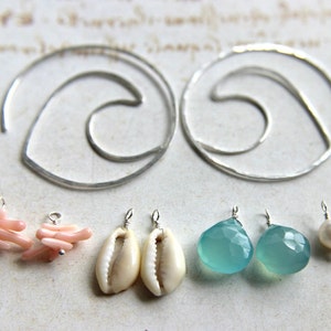 May include: A set of earrings featuring various materials, including silver hoops, pink coral, white seashells, and turquoise gemstones.
