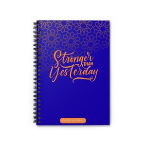 Puede incluir: Cuaderno de espiral con una cubierta azul oscuro. La cubierta presenta el texto "Stronger than Yesterday" en escritura naranja, con un patrón geométrico dorado. La parte inferior de la cubierta tiene el texto "DESIGNED BY HEARTS4TRISTEN".