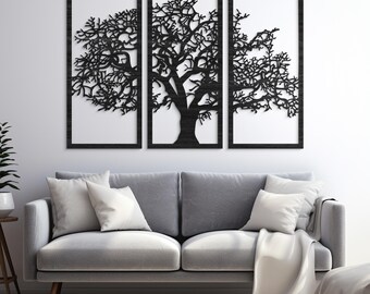 May include: A three-panel wall art set featuring a black tree design. The tree's intricate branches and trunk are set against a white background within dark frames. The artwork is displayed above a gray sofa with white pillows and a blanket.