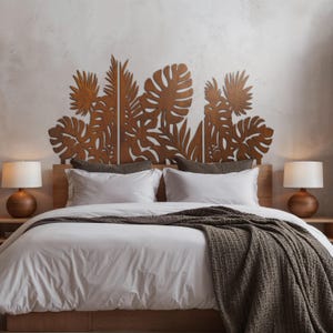 May include: A wooden headboard featuring a tropical leaf design is positioned above a bed with white bedding and a brown throw. Two wooden bedside tables each hold a lamp with a white shade.