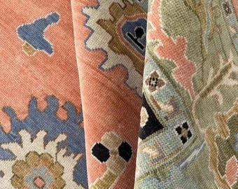 May include: Close-up of three rolled-up area rugs. The rugs feature intricate patterns in shades of peach, blue, green, and brown. The designs include floral and geometric motifs, with a textured appearance. The edges of the rugs are visible.