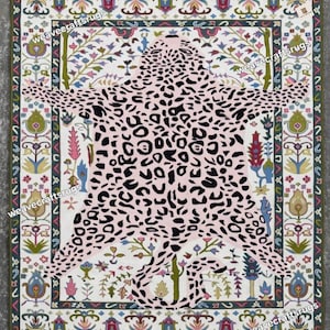 May include: A rectangular rug with a pink leopard print overlaying a white background. The rug has a decorative border with floral and geometric patterns in various colors, including green, blue, and pink. The text "weavecraftsrugs" is visible.