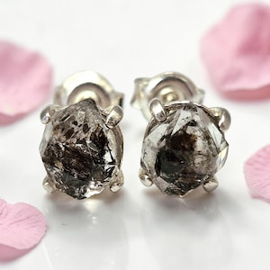 Peut inclure: Une paire de boucles d'oreilles à clous avec des cristaux de quartz bruts, non taillés, de couleur brun foncé et transparent. Chaque pierre présente des inclusions et des facettes naturelles, fixées par des griffes en argent.