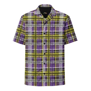 May include: Short-sleeved button-down shirt with a plaid pattern in shades of purple, green, and gray. The shirt has a black collar and black buttons. The text "PUBLIC FICTION" is visible on the collar.