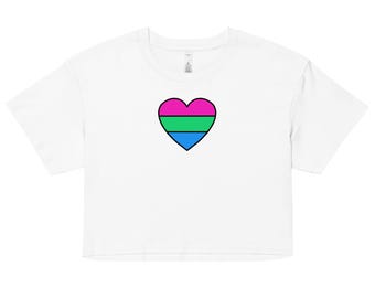 Può includere: Top corto bianco con un disegno a forma di cuore rosa, verde e blu, bordato di nero. La maglietta ha maniche corte e scollo tondo. Il disegno è centrato sul davanti.