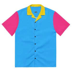 May include: A short-sleeved button-down shirt with a vibrant color-block design. The shirt features a light blue body, bright pink sleeves, and a yellow collar. The text "Kale Culture" is printed on the collar.