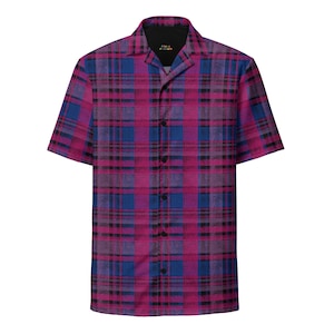 Puede incluir: Camisa de manga corta con un llamativo diseño de cuadros en tonos rosa, azul y negro. La camisa tiene un cuello clásico y un forro interior negro. El texto "FOREVER FISSION" es visible en la etiqueta.