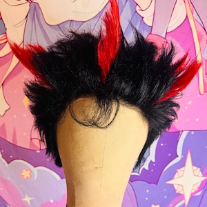 May include: A black wig with red highlights, styled with spiky, layered strands. The wig is displayed on a mannequin head, showcasing the cosplay-style design. The red accents are strategically placed throughout the wig.