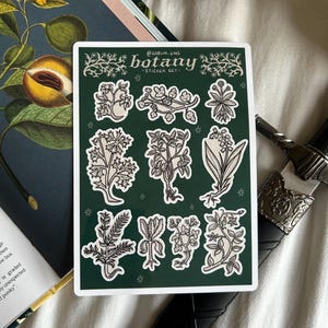 May include: A rectangular sticker sheet with a dark green background featuring nine individual botanical illustrations in white and black ink. The text at the top reads "@GOBLIN_EMS BOTANY ~STICKER SET~" with decorative floral flourishes on both sides.