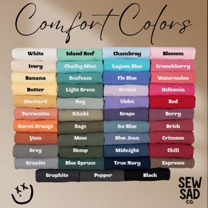 May include: A color chart featuring a variety of Comfort Colors. The image displays a range of hues, including white, blue, green, pink, and brown. Each color is labeled with its name, such as "White," "Lagoon Blue," and "Berry."