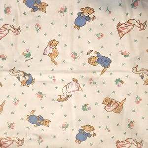 Puede incluir: Tela color crema con un patrón repetido de animales de dibujos animados en varias poses. Los animales son de color marrón, azul y rosa, con acentos florales y verdes. La tela tiene un aspecto vintage y caprichoso.