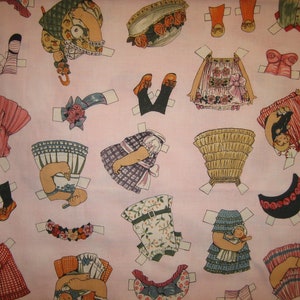 May include: Pink fabric with paper doll cutouts. The dolls are dressed in various outfits, including dresses, skirts, and pants. Some dolls have hats and accessories. The fabric is perfect for crafting and scrapbooking.