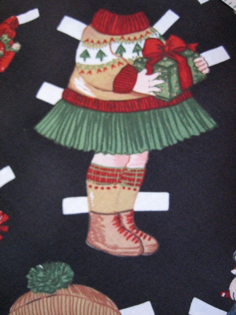 May include: A paper doll illustration of a child in a Christmas outfit. The child wears a tan sweater with green Christmas trees, a green skirt, and red-trimmed socks and boots. The child holds a green gift box with a red bow.