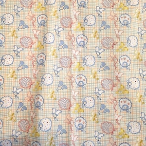 Może przedstawiać: Tkanina z powtarzającym się wzorem kwiatów i abstrakcyjnych kształtów w kolorze niebieskim, czerwonym, żółtym i białym na jasnobeżowym tle w kratkę. Wzór zawiera stylizowane kwiaty i elementy w kształcie kokardek.