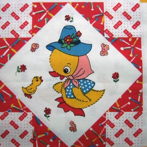 Op de afbeelding: Een vintage quiltblok met een gele eend met een blauwe hoed met rode bloemen en een roze sjaal. De eend is omgeven door rood-witte stof met een kleiner geel kuiken. De quilt heeft een witte achtergrond.