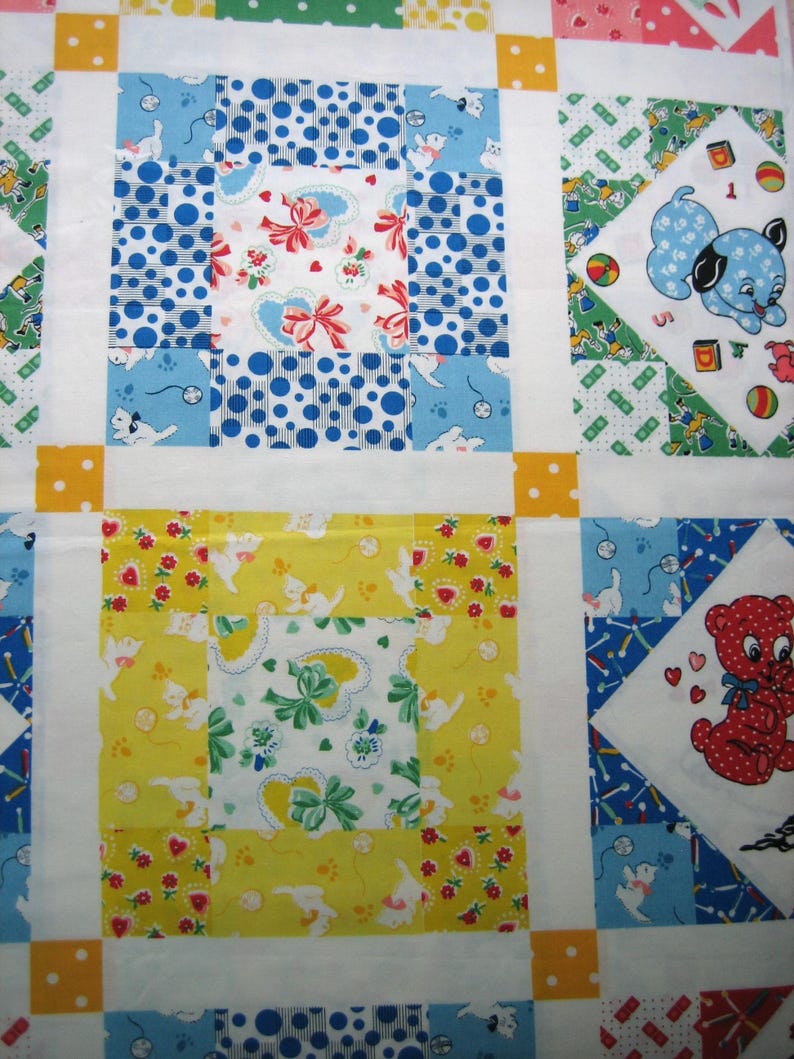 Op de afbeelding: Een patchworkquilt met een herhalend patroon van vierkanten. De vierkanten hebben verschillende ontwerpen, waaronder stippen, bloempatronen en cartoon dieren in tinten blauw, geel, groen en rood. Witte randen en gele stippen accenten maken het ontwerp compleet.