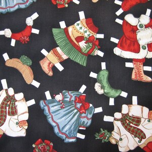 May include: A black fabric featuring a repeating pattern of Christmas-themed paper dolls. The dolls are dressed in festive outfits, including coats, dresses, and hats, with red, green, and white accents. The paper dolls have white tabs.