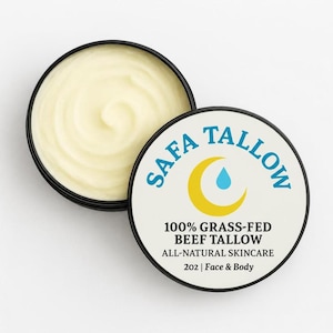 Könnte beinhalten: Ein runder schwarzer Behälter gefüllt mit hellgelber Creme, begleitet von seinem Deckel. Der Deckel zeigt den Text SAFA TALLOW, einen gelben Halbmond mit einem blauen Tropfen sowie 100% GRASS-FED BEEF TALLOW ALL-NATURAL SKINCARE 202 | Face & Body.