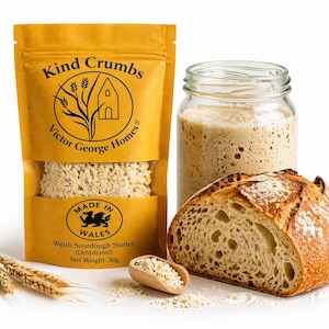 May include: Image of a package of "Kind Crumbs" Welsh Sourdough Starter, a jar of sourdough starter, and a loaf of bread. The package is yellow with black text and a logo. A wooden scoop holds starter. The bread is sliced, showing the texture. Net weight: 30g.