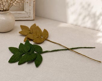 May include: Two decorative felt leaf stems, one in a deep forest green and the other in a muted mustard yellow. Each stem features multiple soft, rounded felt leaves attached to a thin, flexible wire branch, creating a botanical display.