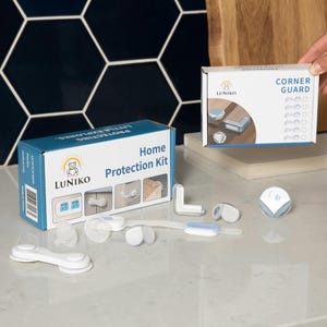 May include: A Luniko Home Protection Kit box and a Corner Guard box, featuring white and blue child safety components including adhesive corner protectors, cabinet locks, and strap locks displayed on a surface with product packaging imagery.