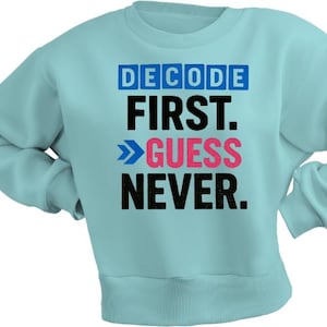 Puede incluir: Sudadera azul claro con las palabras "DECODE FIRST. >GUESS NEVER." en letras azules, negras y rosas. La sudadera tiene cuello redondo y mangas largas.