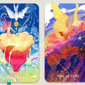 May include: Two tarot cards with colorful illustrations. The "Ace of Cups" card features a fairy figure and a large flower. The "Two of Cups" card depicts an angel-like figure with wings. The cards have a blue and purple background.