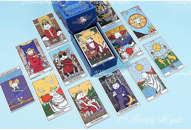 May include: A deck of tarot cards featuring illustrations of dogs in various roles, including The Magician, The Empress, and The High Priestess. The cards are displayed around a blue box with a white fox logo, all set against a light blue background.