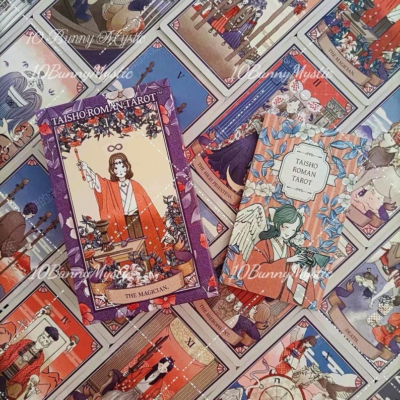 K&ouml;nnte beinhalten: Ein Taisho Roman Tarot-Deck mit einer violetten Schachtel, die die Karte Der Magier zeigt, und einer kleineren rechteckigen Schachtel mit einer Engelsillustration. Beide Schachteln tragen den Text Taisho Roman Tarot inmitten weiterer Karten.