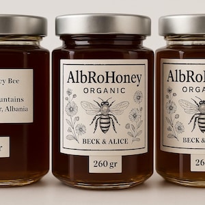May include: Three glass jars of honey with silver lids. The labels read "AlbRoHoney ORGANIC" with a bee illustration and "BECK & ALICE." One jar says "Wild Honey Bee Produced in the mountains of Shkoder, Albania." Weights are 250 g and 260 g.